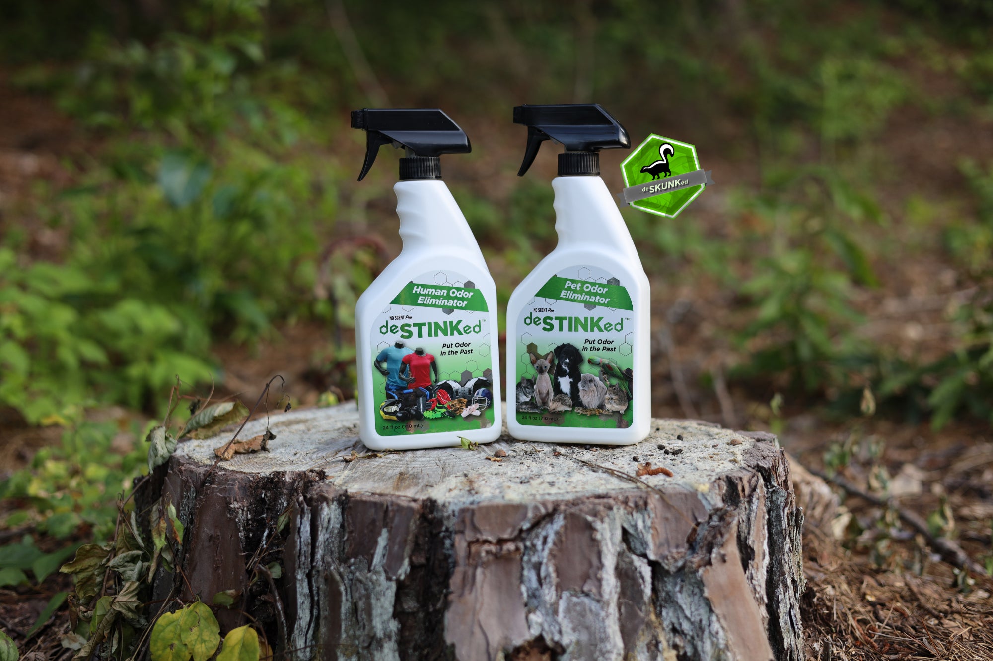 Bottles of deSTINKed Human Odor Eliminator and deSTINKed Pet Odor Eliminator sit on a tree stump.